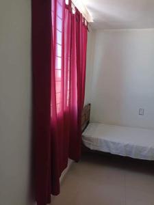 Habitación con cama y cortina roja en Departamento de 4 ambientes dos habitaciones dos baños en Mar del Plata