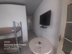 Habitación con mesa blanca y TV en la pared. en Apartamento em Muriqui - RJ - Apto. 202, en Mangaratiba