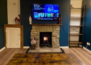 a living room with a fireplace with a flat screen tv at Rustic stone cottage with Hot Tub & fireplace in Crowborough