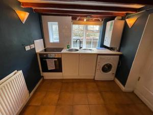 a kitchen with a sink and a washing machine at Rustic stone cottage with Hot Tub & fireplace in Crowborough