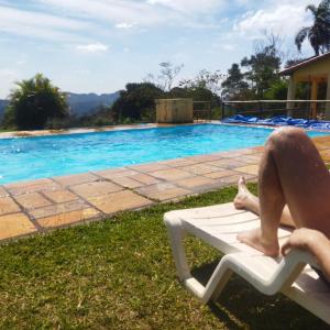 a person sitting on a chair next to a swimming pool at Chácara Áquila in São Roque +69 photos