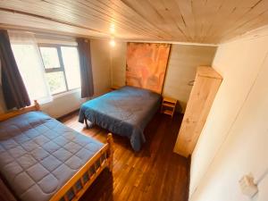 Habitación pequeña con 2 camas y ventana en HOSTAL MIRAFLORES, en Puerto Natales