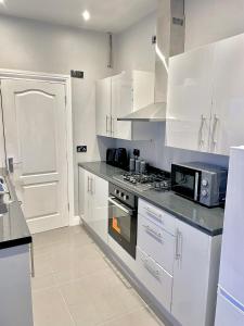 a kitchen with white cabinets and a stove top oven at Central 4 bedroom house in the heart of Birmingham city with Free Parking, and sleeps up to 8! in Birmingham