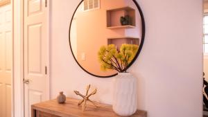 a mirror on a wall with a vase on a table at [1] Chic & Cozy Retreat Walk to KU/Mass/Dining! in Lawrence +7 photos