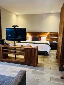 a bedroom with a bed and a desk with a television at El Callejón Hotel Boutique in Oaxaca City