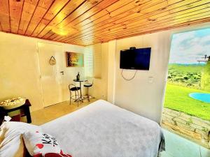 a bedroom with a bed and a flat screen tv at Nostra Casa Valletta in Campos do Jordão