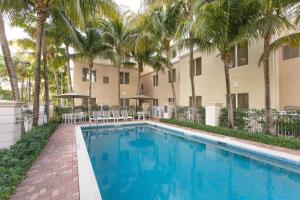 a swimming pool in front of a building with palm trees at Homewood Suites by Hilton Palm Beach Gardens in Palm Beach Gardens