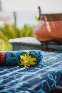 a towel with a yellow flower on top of a bed at Empire Beach Resort ADULTS ONLY in Dhërmi