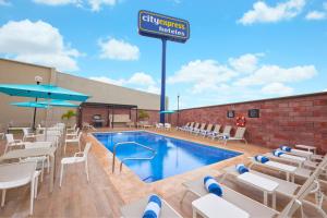 a pool with chairs and a sign that reads filipino hotel at City Express by Marriott Tampico Altamira in Tampico