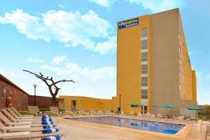 ein Hotelpool mit Stühlen und ein Gebäude in der Unterkunft City Express by Marriott Tampico Altamira in Tampico