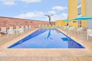 a pool at a hotel with chairs and umbrellas at City Express by Marriott Tampico Altamira in Tampico