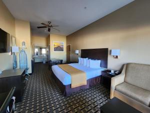 a hotel room with a large bed and a couch at Days Inn by Wyndham Baytown East in Baytown