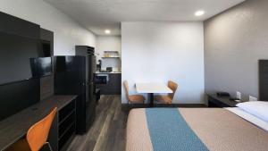 Habitación de hotel con cama, escritorio y mesa. en Studio 6 Galveston TX, en Galveston