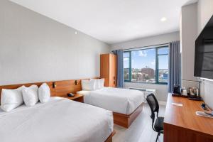 ブルックリンにあるLiberty View Brooklyn Hotelのベッド2台、薄型テレビが備わるホテルルームです。