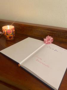 ein Buch mit einer rosa Schleife und einer Kerze auf dem Tisch in der Unterkunft Let It Be Franciacorta in Gussago