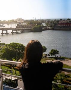 una persona mirando por una ventana a un río en Bahia 79 Apartasuites Cerca al Centro, en Cartagena de Indias