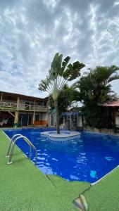 uma piscina azul com uma palmeira em frente a um edifício em HOSTAL SINAGOGA em Montañita