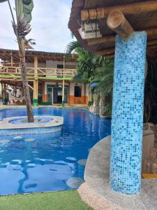 - une piscine dans un complexe doté d'un pilier en carrelage bleu dans l'établissement HOSTAL SINAGOGA, à Montañita