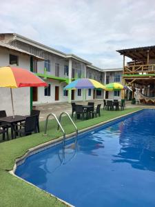 una piscina con sombrillas, mesas y sillas en HOSTAL SINAGOGA en Montañita