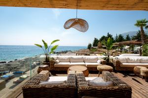 a patio with wicker chairs and tables and the ocean at Empire Beach Resort ADULTS ONLY in Dhërmi