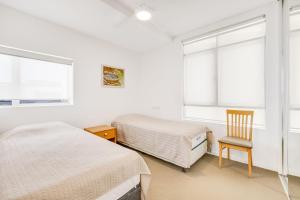a bedroom with two beds and a chair and windows at Sands On Greenmount Unit 4 in Gold Coast