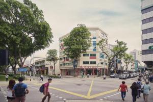 Un gruppo di persone che attraversa una strada in una città di Tai Hoe Hotel a Singapore