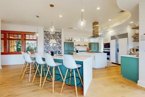 a kitchen with blue cabinets and white stools at Whidbey Wonder in Clinton