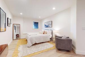 a white bedroom with a bed and a chair at Whidbey Wonder in Clinton