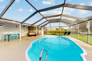 uma piscina com um grande telhado de vidro com uma mesa e cadeiras em Casa Ocaso em Cape Coral
