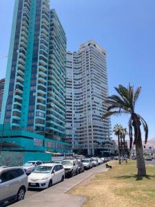 een rij auto's geparkeerd voor hoge gebouwen bij Bella vista departamento amoblado in Iquique