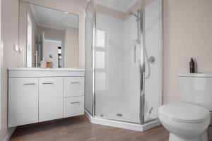 a white bathroom with a shower and a toilet at Relax on Dillon - Waihi Beach Holiday Home in Waihi Beach +16 photos