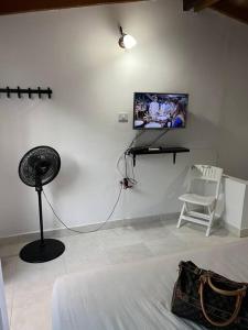 um quarto branco com uma ventoinha e uma televisão na parede em Cabaña de descanso, Rodadero em Gaira