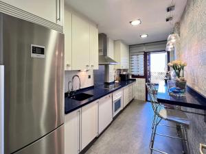a kitchen with white cabinets and a stainless steel refrigerator at Rooftop Pool with Views in Motril