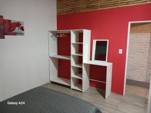 a room with a red wall with shelves and a mirror at Alojamiento el Ancla in San Rafael