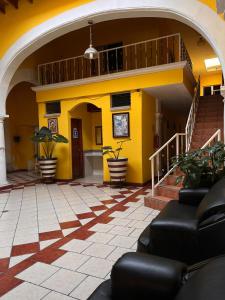 a lobby with a yellow building with chairs and stairs at Hotel Buenos Aires in Durango