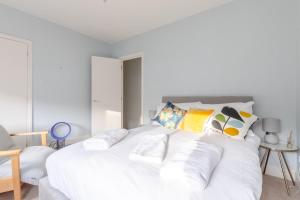 a white bedroom with a large white bed with pillows at Lovely 2BD House on Private Road Clapham Common! in London