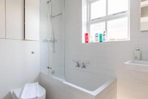 a white bathroom with a toilet and a sink at Lovely 2BD House on Private Road Clapham Common! in London