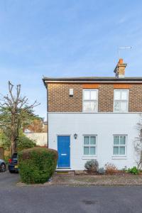 una casa blanca con una puerta azul en Lovely 2BD House on Private Road Clapham Common!, en Londres