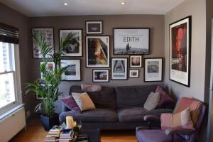 Contemporary 2BD Flat 4 Mins to Finsbury Park! في لندن: غرفة معيشة مع أريكة وصور على الحائط