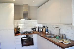 a white kitchen with a sink and a stove at Contemporary 2BD Flat 4 Mins to Finsbury Park! in London