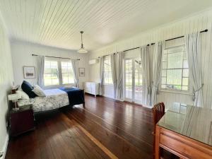1 dormitorio con 1 cama, suelo de madera y ventanas en The Cottage Farm Stay - Grandchester en Grandchester
