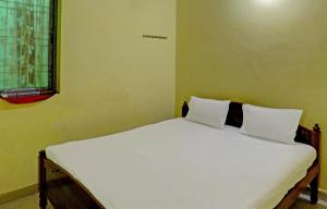 um quarto com uma cama com lençóis brancos e uma janela em OYO Hotel RS Guest House em Katni