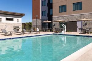 a swimming pool with chairs and a building at Residence Inn by Marriott Fairfield Napa in Fairfield