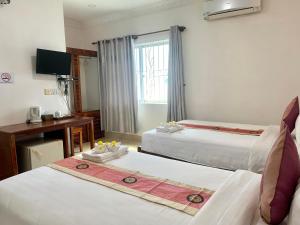 a hotel room with two beds and a desk at The One by Nika in Siem Reap