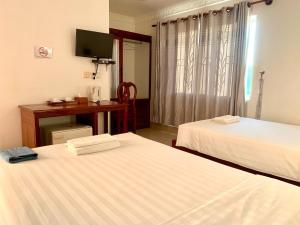 a room with two beds and a desk and a television at The One by Nika in Siem Reap