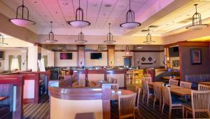a restaurant with tables and chairs and a bar at Wyndham Flint MI Grand Blanc Bishop Airport Conference Ct in Flint