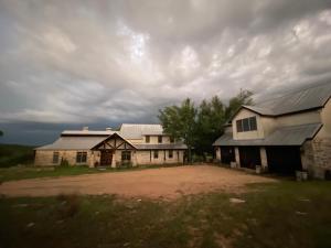 un antiguo granero y una casa con un cielo nublado en V700 Ranch Stays (Guesthouse)-A Tucked Away Gem, en Marble Falls