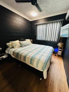 1 dormitorio con 1 cama con manta a cuadros y ventana en Holiday at Henry St West End, Townsville QLD 3 night min, en North Ward
