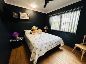 een zwarte slaapkamer met een bed en een raam bij Holiday at Henry St West End, Townsville QLD 3 night min in North Ward