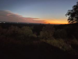 una puesta de sol sobre un campo con árboles y arbustos en V700 Ranch Stays (Guesthouse)-A Tucked Away Gem, en Marble Falls